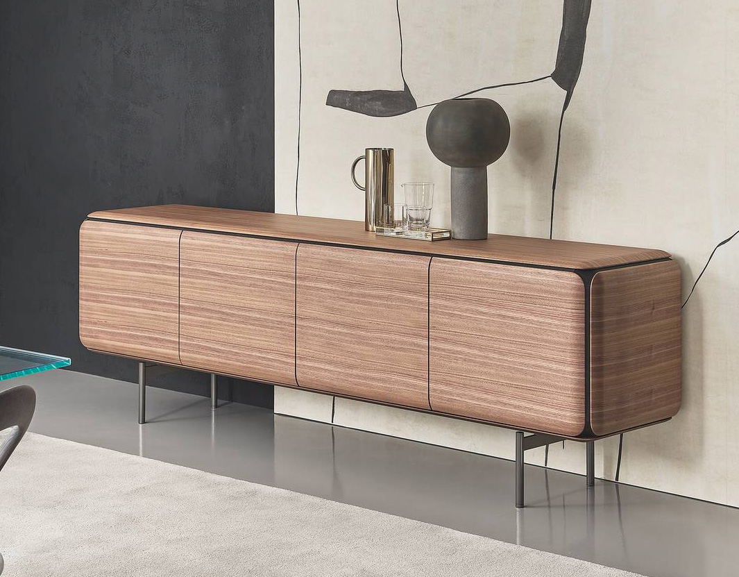 Pregiato noce canaletta per la credenza dalla forma organica Pebble di Porada: è dotata di quattro ante con apertura push-pull e di una sottile base in metallo nella finitura peltro che alleggerisce la struttura. All'interno contiene tre vani, un ripiano centrale in frassino tinto grigio e una serie di ripiani laterali in cristallo fumé. Misura L 240 x P 55 x H 74 cm. Prezzo 13.118 euro. www.porada.it