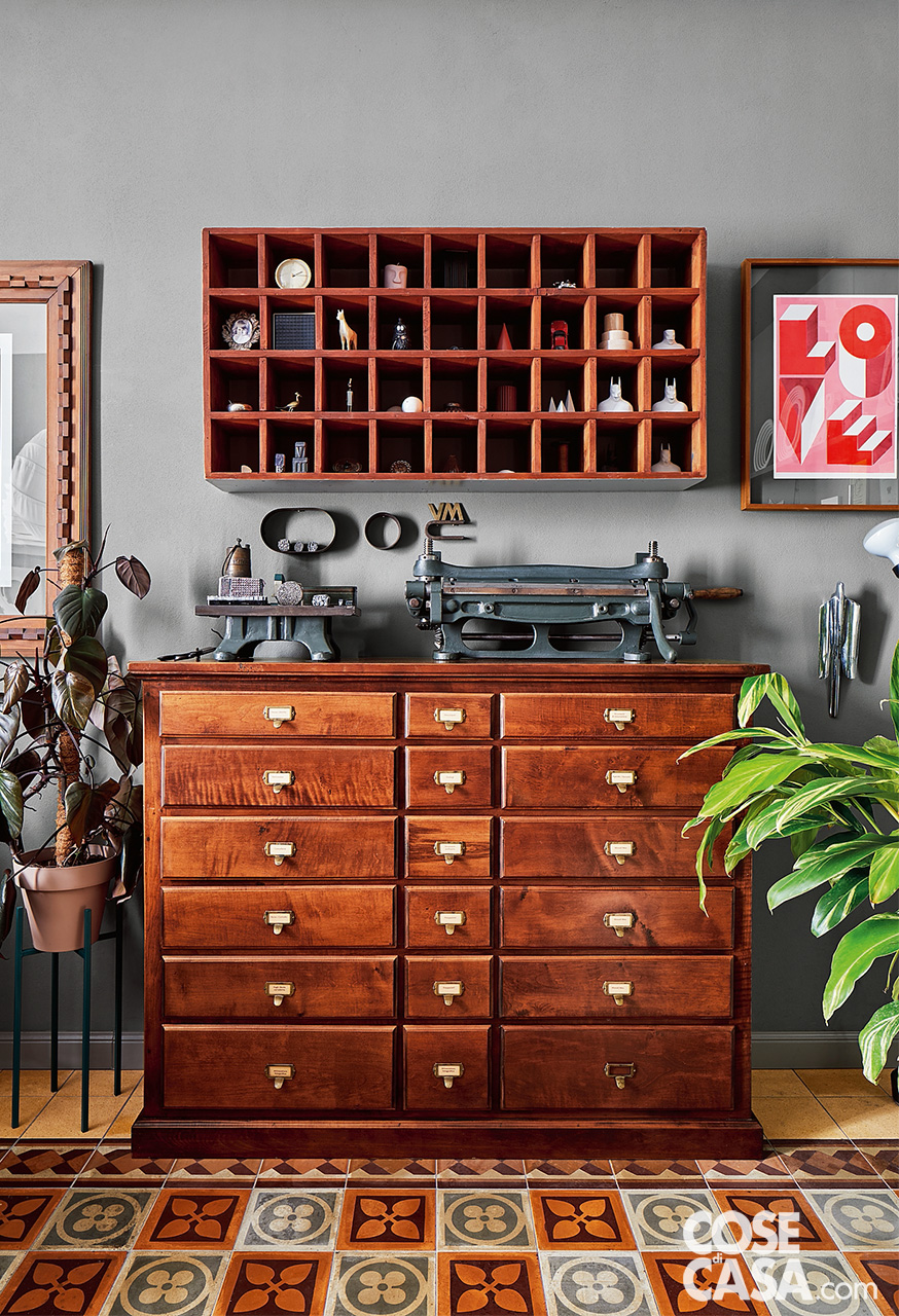 Cassettiera e pensile con piccoli vani a giorno provenienti da antichi spazi di lavoro arredano lo studio con pavimento in cementine originali