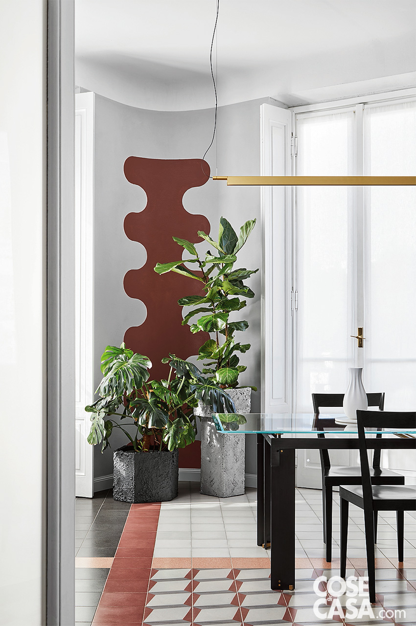 Angolo decorato della zona pranzo arredata con tavolo cristallo e gambe nere