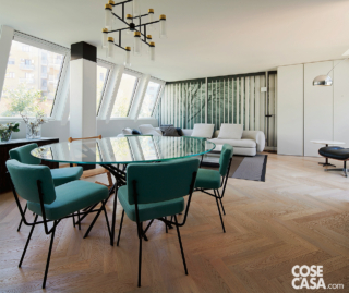 Zona pranzo illuminata da una serie di finestre sul tetto arredata con tavolo di cristallo rotondo Zona pranzo illuminata da una serie di finestre sul tetto arredata con tavolo di cristallo rotondo