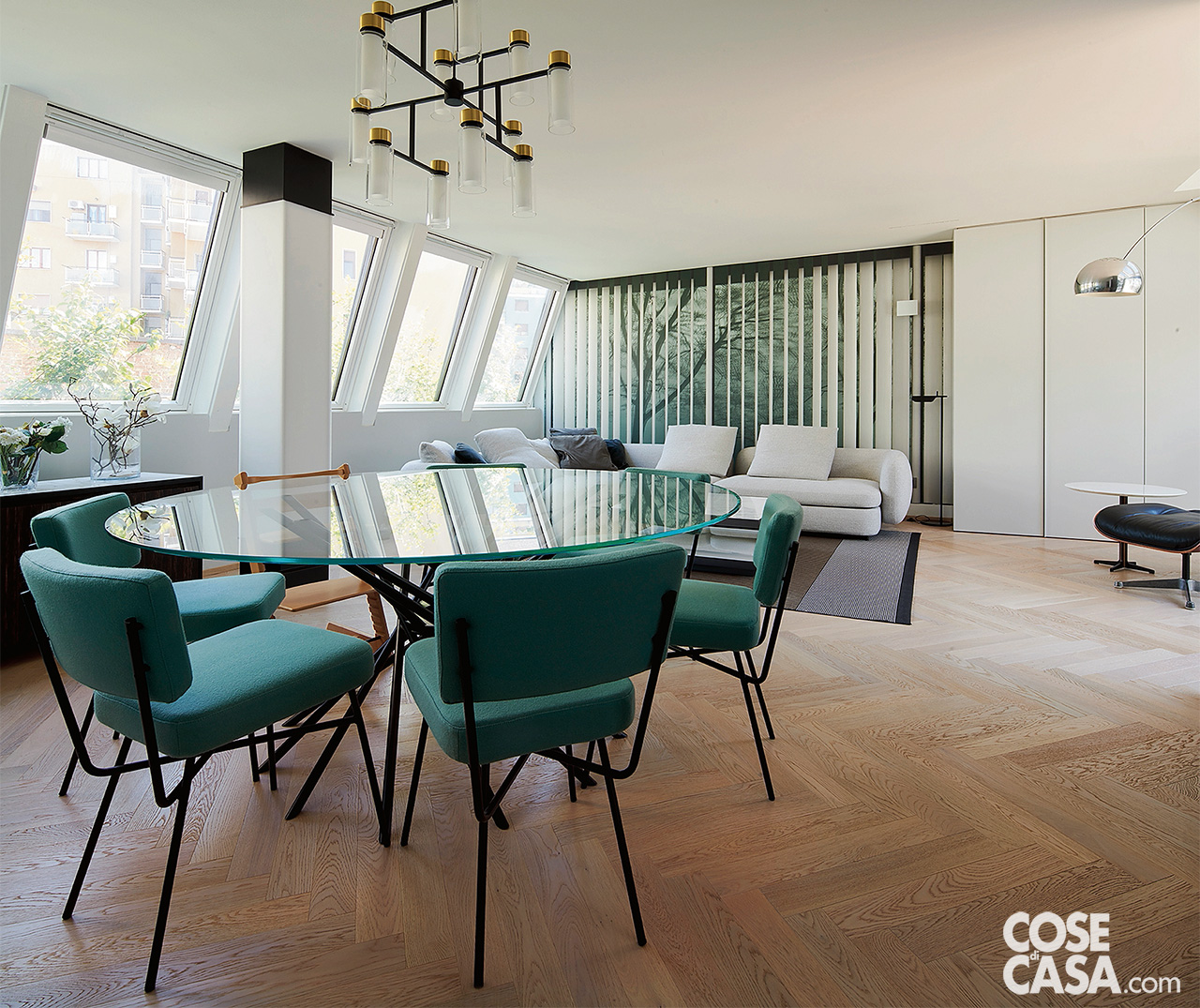 Zona pranzo illuminata da una serie di finestre sul tetto arredata con tavolo di cristallo rotondo Zona pranzo illuminata da una serie di finestre sul tetto arredata con tavolo di cristallo rotondo