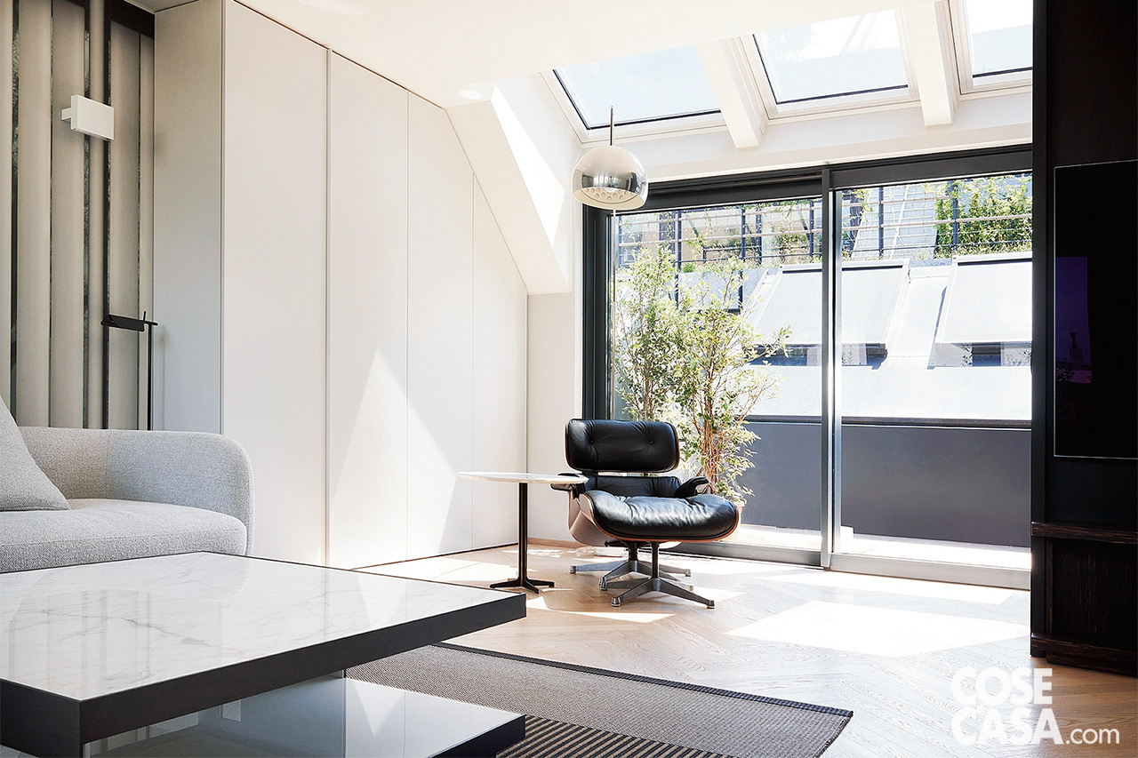 Zona relax nel living con poltrona nera in piena luce sotto le finestre sul tetto e davanti alla parete vetrata Zona relax nel living con poltrona nera in piena luce sotto le finestre sul tetto e davanti alla parete vetrata