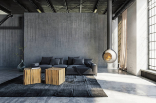 Qui il grigio non è un dettaglio, ma l’assoluto protagonista: avvolge pareti, pavimento, soffitto e divano, trasformando lo spazio in un interno dal carattere fortemente contemporaneo e quasi scultoreo. La parete materica (ottenuta con decorativo concrete, realizzato con Ard Lime Intonachino, intonaco minerale a base di grassello di calce e ArdCreative Velature, finitura silossanica decorativa all’acqua a effetto antichizzato, entrambi di Ard Raccanello, www.ard-raccanello.it) esalta le sfumature del cemento, il divano grigio antracite si mimetizza nella palette, accentuando la sensazione di continuità e omogeneità cromatica, il tappeto tono su tono rafforza l’effetto monocromatico, ma con le sue ombre aggiunge movimento visivo. A rompere questa compattezza arrivano pochi elementi scelti con cura: i tavolini in legno naturale, che introducono calore e matericità, e il camino sospeso, scultura funzionale che con il suo bagliore crea un contrasto caldo con le tonalità fredde circostanti. Qui il grigio non è un dettaglio, ma l’assoluto protagonista: avvolge pareti, pavimento, soffitto e divano, trasformando lo spazio in un interno dal carattere fortemente contemporaneo e quasi scultoreo. La parete materica (ottenuta con decorativo concrete, realizzato con Ard Lime Intonachino, intonaco minerale a base di grassello di calce e ArdCreative Velature, finitura silossanica decorativa all’acqua a effetto antichizzato, entrambi di Ard Raccanello, www.ard-raccanello.it) esalta le sfumature del cemento, il divano grigio antracite si mimetizza nella palette, accentuando la sensazione di continuità e omogeneità cromatica, il tappeto tono su tono rafforza l’effetto monocromatico, ma con le sue ombre aggiunge movimento visivo. A rompere questa compattezza arrivano pochi elementi scelti con cura: i tavolini in legno naturale, che introducono calore e matericità, e il camino sospeso, scultura funzionale che con il suo bagliore crea un contrasto caldo con le tonalità fredde circostanti.
