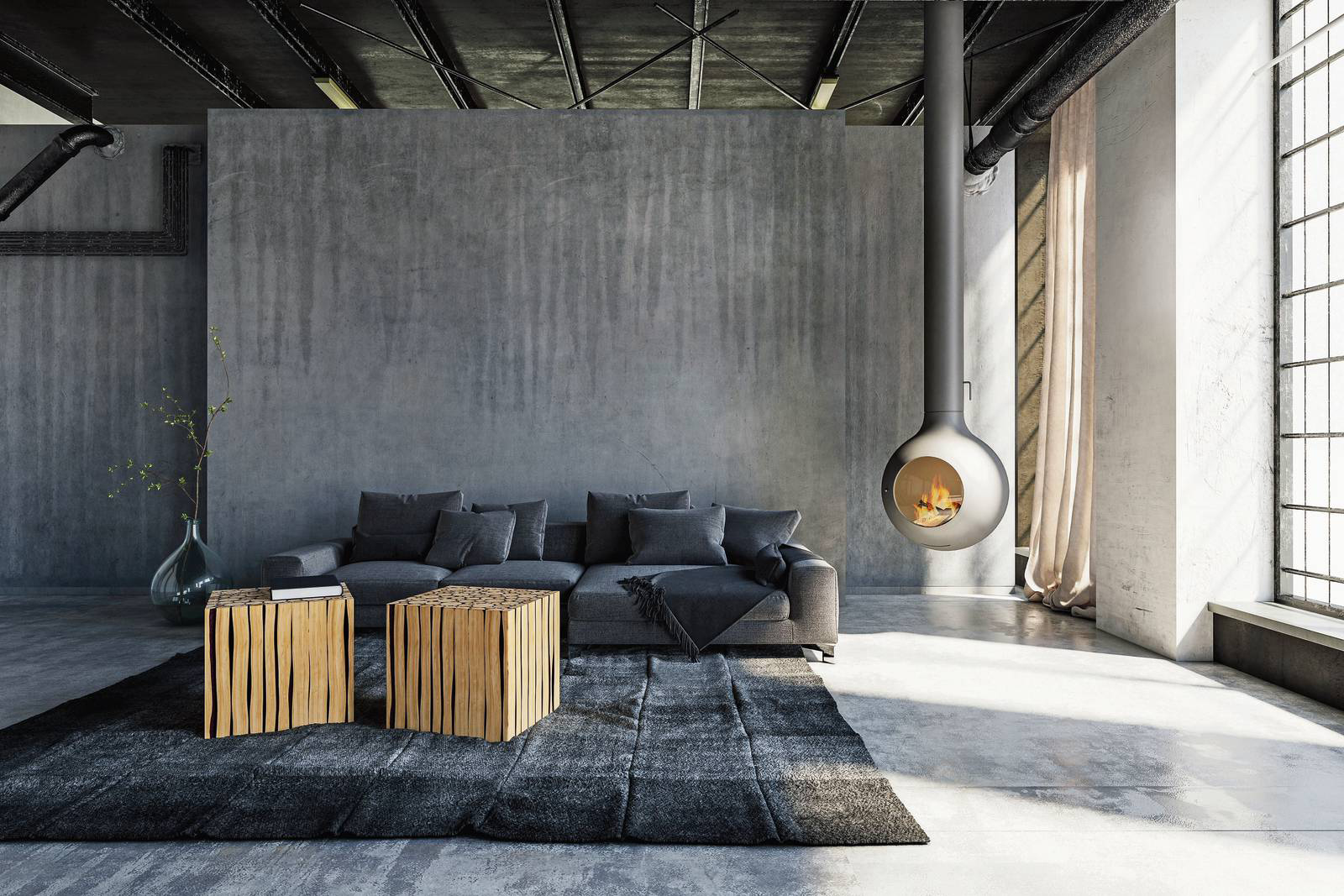 Qui il grigio non è un dettaglio, ma l’assoluto protagonista: avvolge pareti, pavimento, soffitto e divano, trasformando lo spazio in un interno dal carattere fortemente contemporaneo e quasi scultoreo. La parete materica (ottenuta con decorativo concrete, realizzato con Ard Lime Intonachino, intonaco minerale a base di grassello di calce e ArdCreative Velature, finitura silossanica decorativa all’acqua a effetto antichizzato, entrambi di Ard Raccanello, www.ard-raccanello.it) esalta le sfumature del cemento, il divano grigio antracite si mimetizza nella palette, accentuando la sensazione di continuità e omogeneità cromatica, il tappeto tono su tono rafforza l’effetto monocromatico, ma con le sue ombre aggiunge movimento visivo. A rompere questa compattezza arrivano pochi elementi scelti con cura: i tavolini in legno naturale, che introducono calore e matericità, e il camino sospeso, scultura funzionale che con il suo bagliore crea un contrasto caldo con le tonalità fredde circostanti.