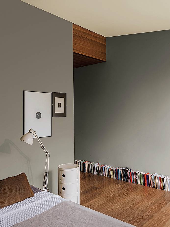 Tutta la stanza è stata dipinta di grigio (pittura decorativa grigia Color Collection grigio KK 67 Absolute di Kerakoll, www.kerakoll.com) con la sola eccezione del soffitto bianco, creando così un effetto ovattato. L'arredo è essenziale, ridotto al minimo, ma grazie a dettagli in legno come il parquet e il letto, la sensazione non è asettica o fredda, ma ordinata e pulita. Da notare il particolare dei libri semplicemente appoggiati  sul pavimento, che aggiunge  un tocco molto personale.