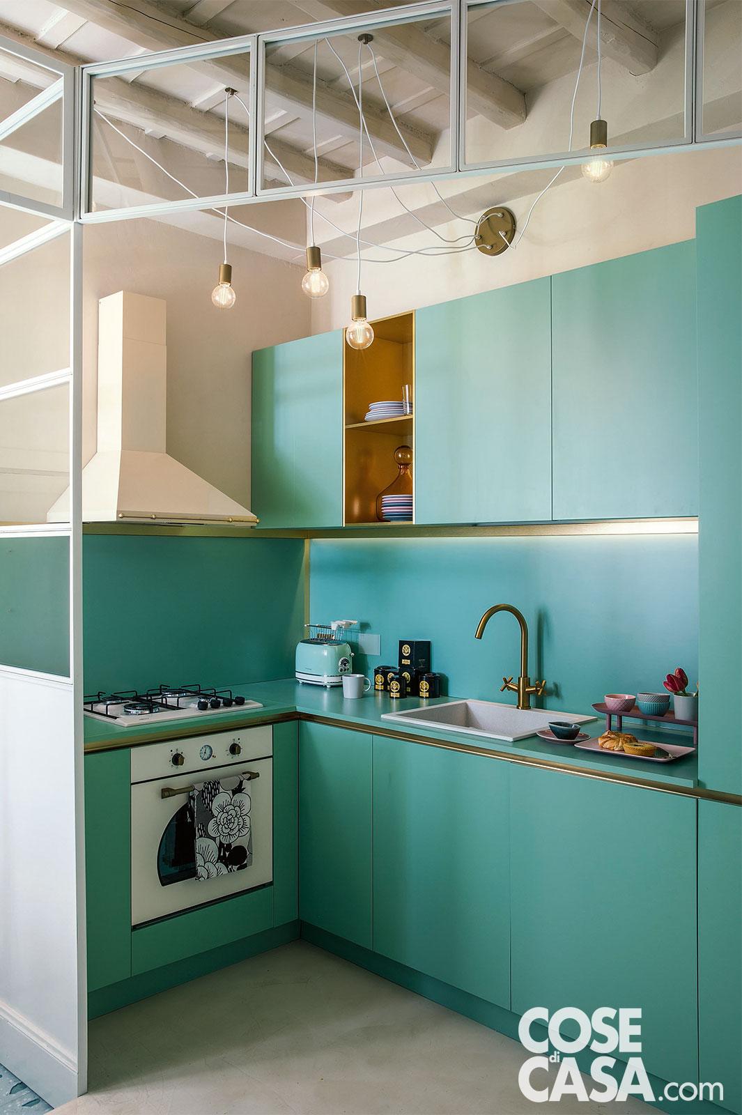 La composizione cucina a L, su due lati, color verde acqua è a vista, aperta ma circoscritta da una struttura realizzata su disegno dal fabbro in ferro laccato bianco e vetro, un involucro che la delimita nella parte superiore e ai due lati del vano d'accesso. Il forno con estetica in vetro temperato bianco e il piano cottura a gas sono di Elleci. Originale l'idea della lampada destrutturata con placca a parete e cavi a vista. Progetto: arch. Ilaria Bellia. Foto: Studio Wolo. La composizione cucina a L, su due lati, color verde acqua è a vista, aperta ma circoscritta da una struttura realizzata su disegno dal fabbro in ferro laccato bianco e vetro, un involucro che la delimita nella parte superiore e ai due lati del vano d'accesso. Il forno con estetica in vetro temperato bianco e il piano cottura a gas sono di Elleci. Originale l'idea della lampada destrutturata con placca a parete e cavi a vista. Progetto: arch. Ilaria Bellia. Foto: Studio Wolo.