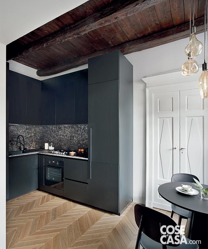 In un contesto “importante”, con soffitti alti in legno con travi a vista, vecchi camini, nicchie nei muri portanti, porte interne a doppio battente, la piccola cucina ad angolo nera risulta sofisticata ed elegante, con mobili rivestiti in laminato opaco (di Miton) abbinati a un'alzata in laminato HPL che riproduce l'aspetto della pietra naturale. La zona pranzo è sistemata nell'angolo vicino alla finestra, sul lato opposto rispetto alla composizione a L. Progetto: arch. Valentina Farassino. Foto: Barbara Corsico, styling Chiara Dal Canto. In un contesto “importante”, con soffitti alti in legno con travi a vista, vecchi camini, nicchie nei muri portanti, porte interne a doppio battente, la piccola cucina ad angolo nera risulta sofisticata ed elegante, con mobili rivestiti in laminato opaco (di Miton) abbinati a un'alzata in laminato HPL che riproduce l'aspetto della pietra naturale. La zona pranzo è sistemata nell'angolo vicino alla finestra, sul lato opposto rispetto alla composizione a L. Progetto: arch. Valentina Farassino. Foto: Barbara Corsico, styling Chiara Dal Canto.