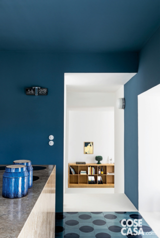 Per l’area cucina è stato scelta una tinteggiatura marina su pareti e soffitto, a contrasto con il blocco isola, mentre dialoga con il pavimento in due toni di blu.