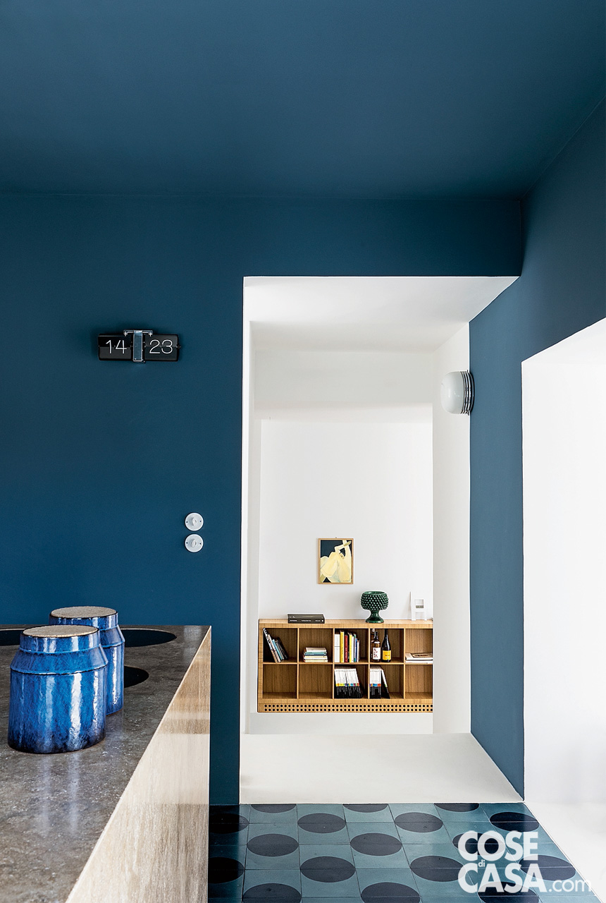 Per l’area cucina è stato scelta una tinteggiatura marina su pareti e soffitto, a contrasto con il blocco isola, mentre dialoga con il pavimento in due toni di blu.