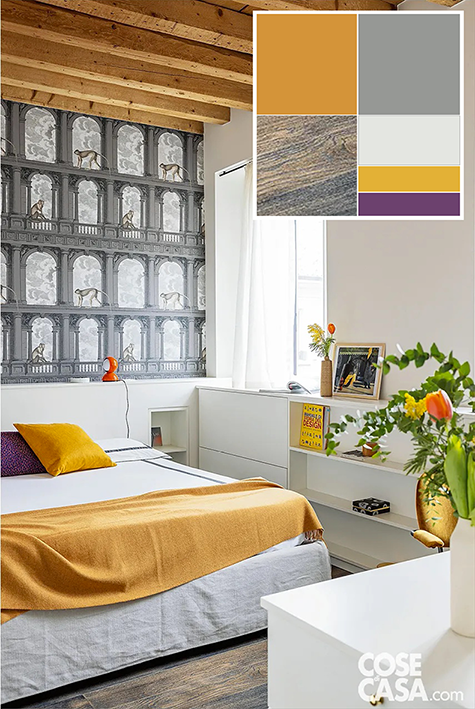 Nella stanza, il bianco dominante è punteggiato da accenti cromatici di giallo ocra che contraddistinguono gli interni nel loro insieme. Plaid e cuscino ocra scaldano un ambiente perlopiù neutro, con mobili e pareti bianche e tappezzeria grigia dietro al letto, incorniciata in alto dalle travi a vista e in basso dalla testiera attrezzata. L’effetto trompe-l’oeil di questa “facciata” aumenta visivamente la profondità dell’ambiente. Foto: Cristina Galliena Bohman – Styling: Laura Mauceri. Progetto architettonico, progetto di interni: bilune studio – interior design e architettura – Silvana Tombini interior designer - Direzione lavori: arch. Stefania Denora.