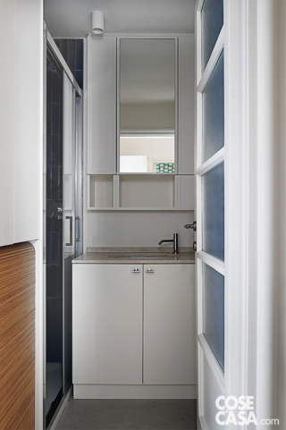 Bagno di servizio con mobili su misura e lavanderia integrata - Specchio contenitore e piano in travertino sopra lavabo sottopiano; sulla sinistra, armadiatura in rovere con vano per la lavatrice Bagno di servizio con mobili su misura e lavanderia integrata - Specchio contenitore e piano in travertino sopra lavabo sottopiano; sulla sinistra, armadiatura in rovere con vano per la lavatrice