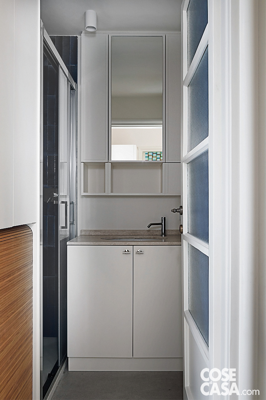 Bagno di servizio con mobili su misura e lavanderia integrata  - Specchio contenitore e piano in travertino sopra lavabo sottopiano; sulla sinistra, armadiatura in rovere con vano per la lavatrice Bagno di servizio con mobili su misura e lavanderia integrata  - Specchio contenitore e piano in travertino sopra lavabo sottopiano; sulla sinistra, armadiatura in rovere con vano per la lavatrice