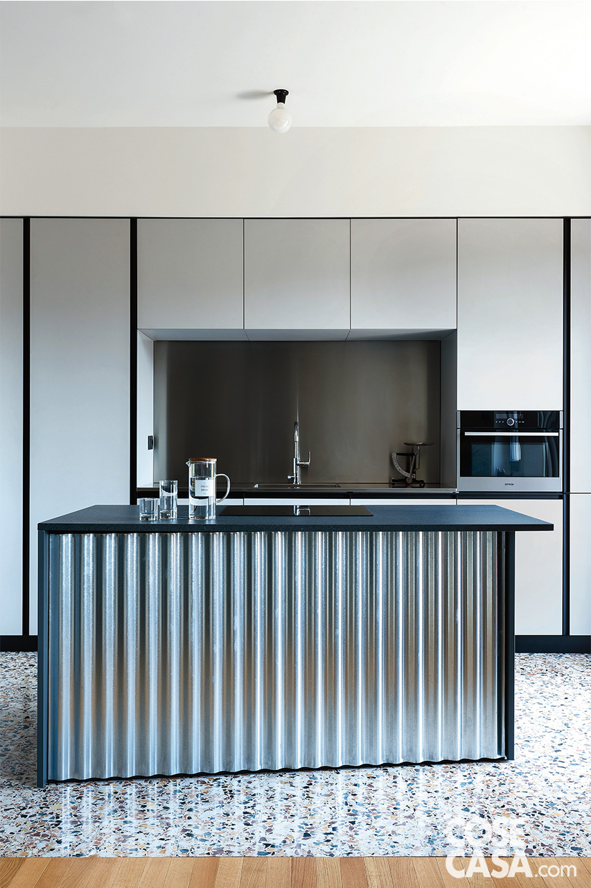 La cucina a vista sul soggiorno ha il proprio punto focale nell’isola centrale con il piano cottura: un parallelepipedo rivestito in lamiera zincata ondulata con top in pietra lavica La cucina a vista sul soggiorno ha il proprio punto focale nell’isola centrale con il piano cottura: un parallelepipedo rivestito in lamiera zincata ondulata con top in pietra lavica