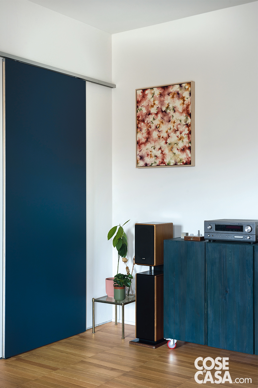 Uno scorcio del soggiorno adiacente all’ingresso. La parete bianca sopra il mobile blu - che contiene l’impianto audio - viene usata come superficie neutra per le proiezioni video. Uno scorcio del soggiorno adiacente all’ingresso. La parete bianca sopra il mobile blu - che contiene l’impianto audio - viene usata come superficie neutra per le proiezioni video.