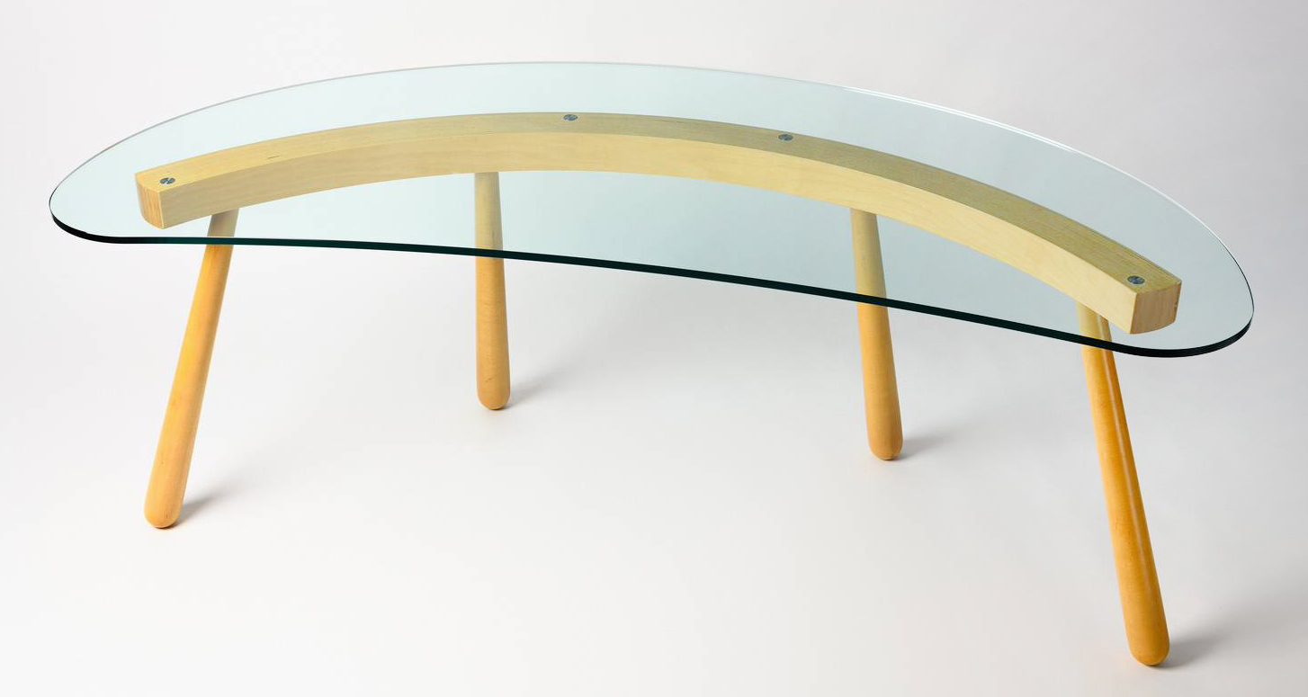 La scrivania Boomerang di Gebrüder Thonet Vienna, disegnata da Enzo Mari, è caratterizzata da una trave in lamellare di faggio curvata e da quattro gambe robuste, ma slanciate in faggio massello. Il piano, in vetro temperato extrachiaro, segue la forma curvilinea della base, dando vita ad un effetto dinamico e leggero allo stesso tempo. https://www.gebruederthonetvienna.com - Salone del mobile 2025, padiglione 22, Stand A20. La scrivania Boomerang di Gebrüder Thonet Vienna, disegnata da Enzo Mari, è caratterizzata da una trave in lamellare di faggio curvata e da quattro gambe robuste, ma slanciate in faggio massello. Il piano, in vetro temperato extrachiaro, segue la forma curvilinea della base, dando vita ad un effetto dinamico e leggero allo stesso tempo. https://www.gebruederthonetvienna.com - Salone del mobile 2025, padiglione 22, Stand A20.