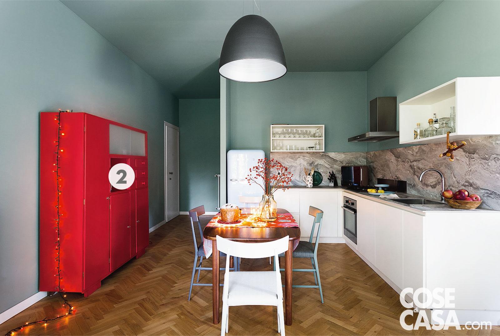 La cucina bianca si staglia su uno sfondo verde, valorizzata anche dal piano e dall'alzata in laminato effetto marmo. Al posto di pensili chiusi due moduli a giorno. Progetto: arch. Nicola Carnevali. Foto: Studio Roy. Styling: Lidia Elisa Covello.
