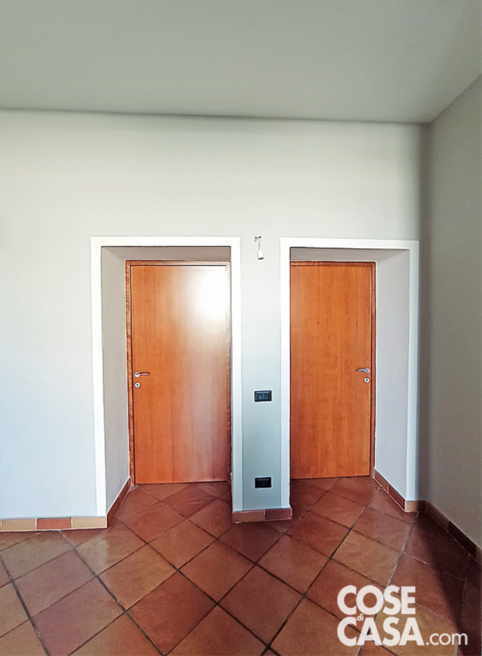 ERA COSI'
Le due porte in legno dello studio e della camera, che si aprono nel muro di spina di elevato spessore, sono state sostituite da modelli rasomuro, avanzate di oltre mezzo metro in modo da formare una linea continua a filo della parete e rivestite infine con la carta da parati.