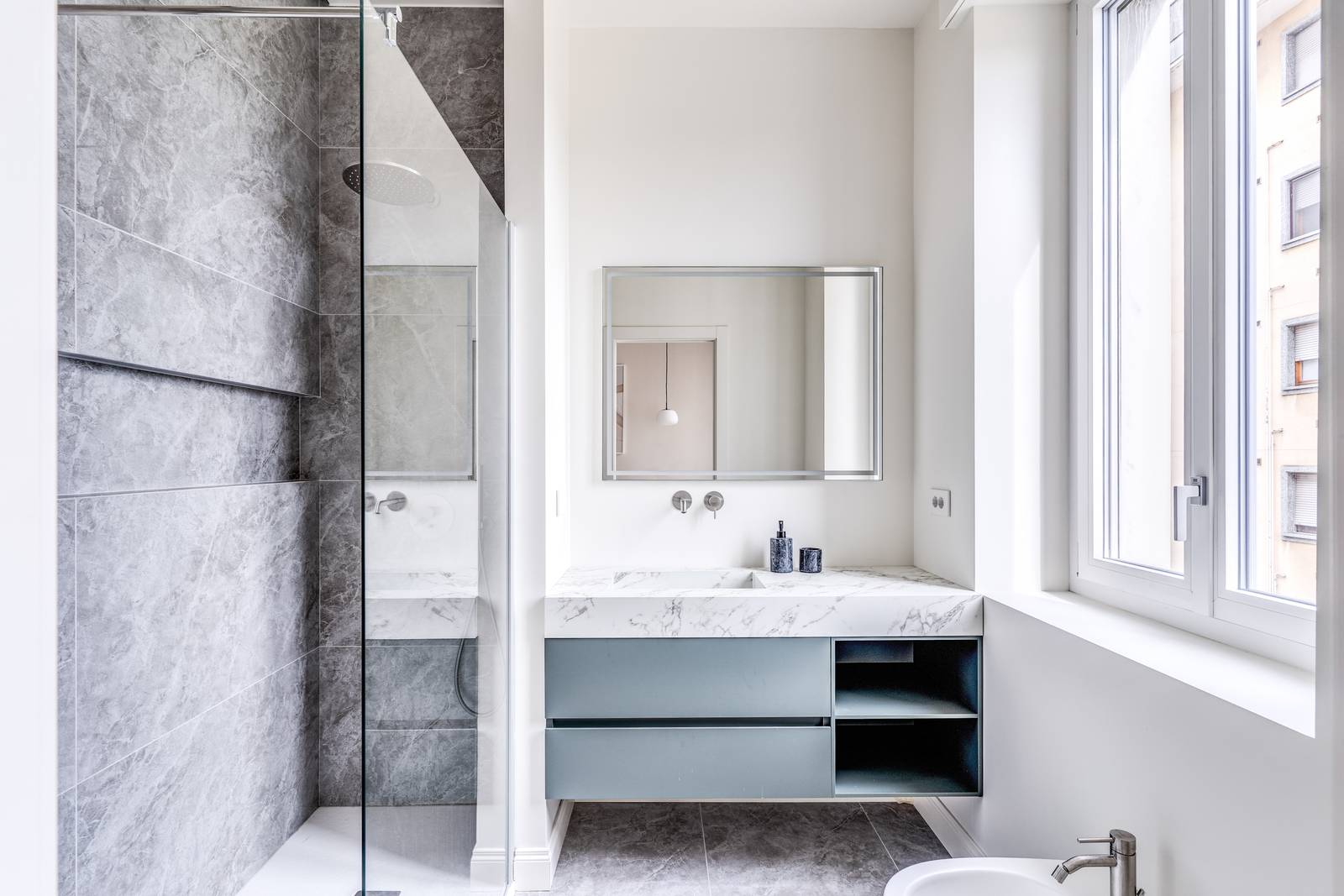 Uno dei bagni si sviluppa in lunghezza, con un'ampia doccia e un mobile lavabo elegante e pratico.