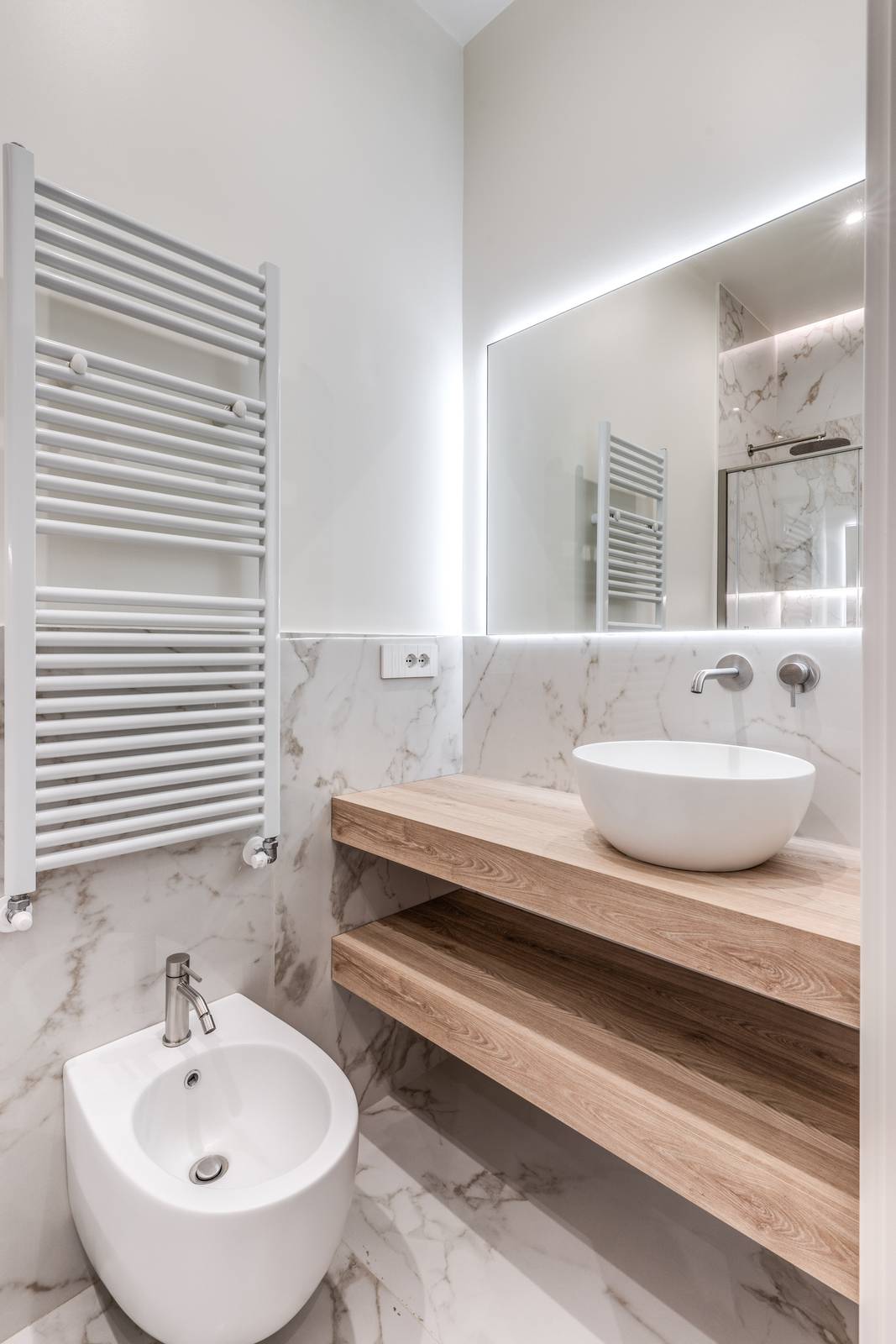 Effetto marmo per le piastrelle del bagno, eleganti e "scaldate" dal legno del mobile lavabo.