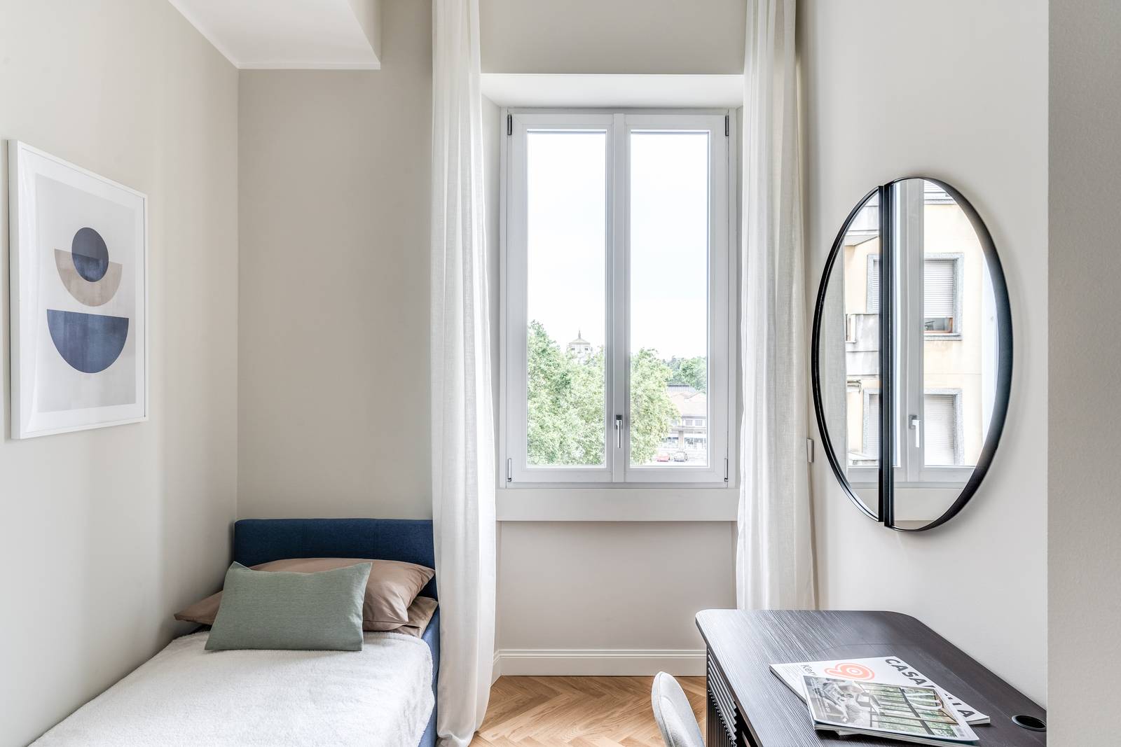 La scrivania di colore scuro e il bordo dello specchio creano un elegante contrasto con i colori chiari dell'ambiente.