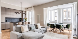 Casa con finestra Oknoplat a Milano via Arnaldo. La zona giorno è un open space che comprende il salotto, la zona pranzo e la cucina, tutti con il medesimo pavimento in parquet.