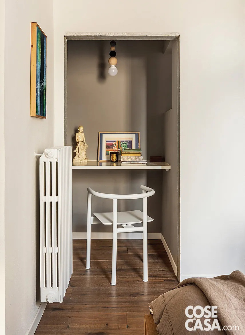 In questa camera da letto matrimoniale dai toni naturali e soft, lungo una parete laterale al letto è presente una nicchia di 60 centimetri di profondità. Essa, che è stata evidenziata rispetto alle pareti bianche della stanza con una tinteggiatura di colore grigio, ospita una postazione studio realizzata con un semplice piano sospeso e una sedia di legno bianco ed è illuminata da una lampada a sospensione.
Progetto O/A Officina Abitare, architetti Sara Bartolini e Matteo Pierattini, via Cairoli 41, Firenze officinaabitare.com - Foto Studio Daido - Styling Studio Wolo