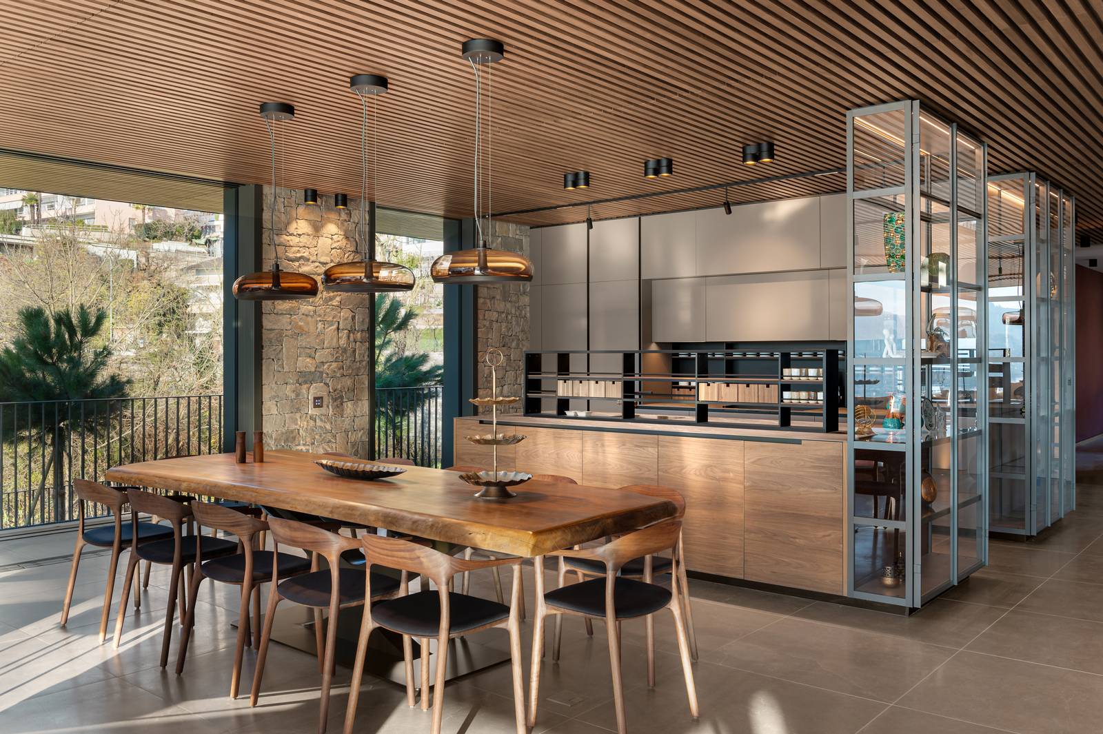Vista della zona pranzo e cucina, con pavimentazione in Lithos Desert 14 mm di Cotto d'Este. Si notano il grande tavolo in legno massello, l'illuminazione moderna e la parete esterna in pietra a vista, che crea un ponte tra l'interno e l'ambiente circostante. Vista della zona pranzo e cucina, con pavimentazione in Lithos Desert 14 mm di Cotto d'Este. Si notano il grande tavolo in legno massello, l'illuminazione moderna e la parete esterna in pietra a vista, che crea un ponte tra l'interno e l'ambiente circostante.