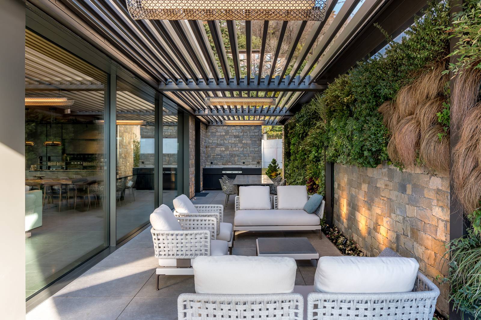 Zona living esterna sotto una pergola, con comodi arredi outdoor. Le pareti in pietra a vista e il pavimento in gres effetto pietra creano un ambiente accogliente e resistente, ideale per il relax all'aperto. Zona living esterna sotto una pergola, con comodi arredi outdoor. Le pareti in pietra a vista e il pavimento in gres effetto pietra creano un ambiente accogliente e resistente, ideale per il relax all'aperto.