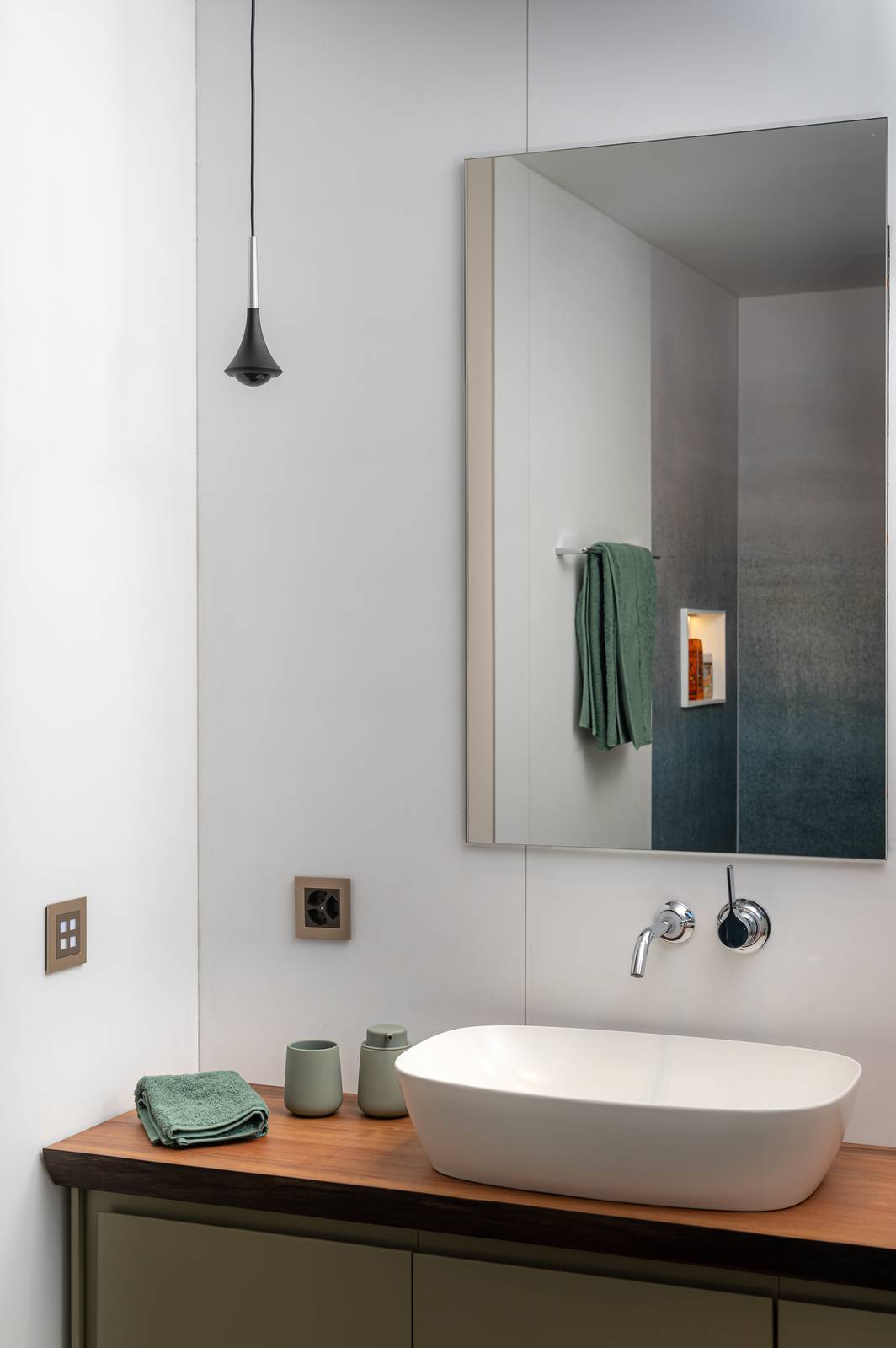 Dettaglio del bagno con il lavabo a catino su mobile in legno. La parete dietro lo specchio è rivestita con Wonderwall di Cotto d'Este in una finitura bianca, che aggiunge un tocco di eleganza all'ambiente proteggendo la parete. Dettaglio del bagno con il lavabo a catino su mobile in legno. La parete dietro lo specchio è rivestita con Wonderwall di Cotto d'Este in una finitura bianca, che aggiunge un tocco di eleganza all'ambiente proteggendo la parete.