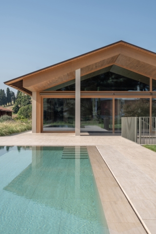 L'esterno della villa in Brianza con zona giorno che guarda verso la piscina a sfioro con copertura in travertino. L'esterno della villa in Brianza con zona giorno che guarda verso la piscina a sfioro con copertura in travertino.