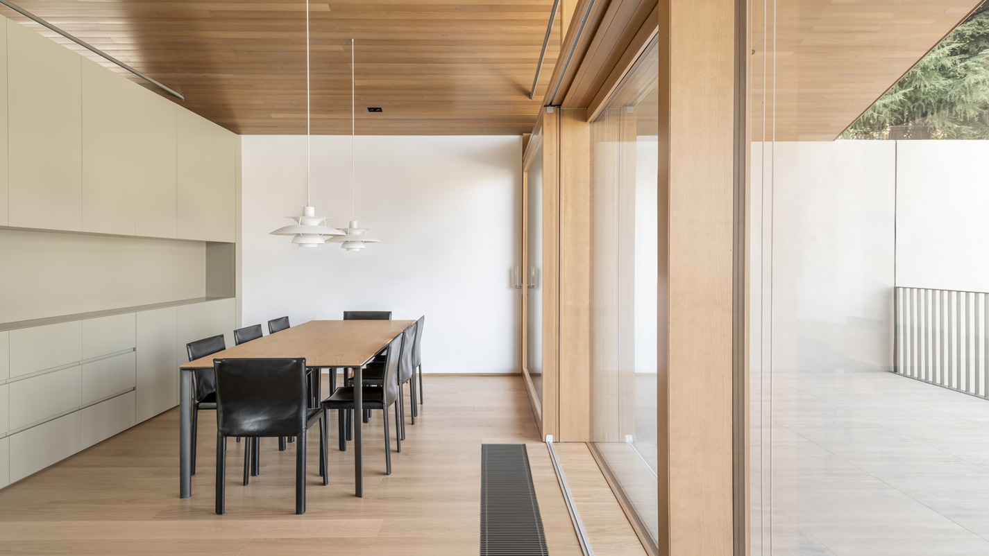 La zona pranzo con il suo grande tavolo rettangolare arredato con sedie moderne a contrasto è contornata da una vetrata ampia.