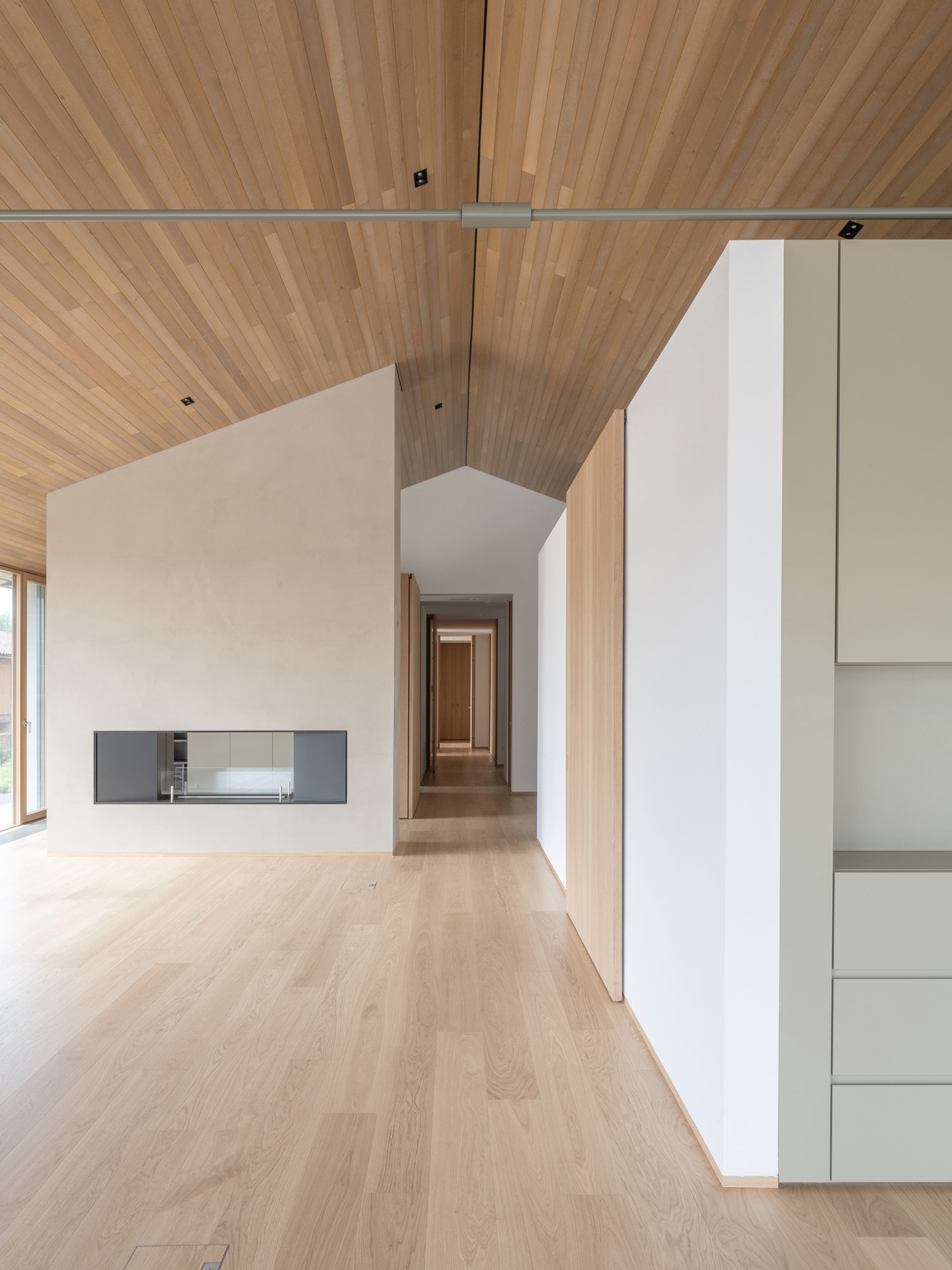 Il pavimento in assi di legno dialoga con i listelli sottili che definiscono il soffitto.