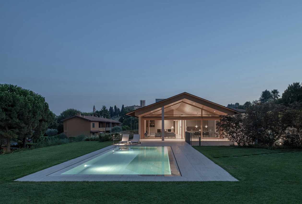 Vista notturna della villa in Brianza con piscina illuminata e spazio verde delimitato.