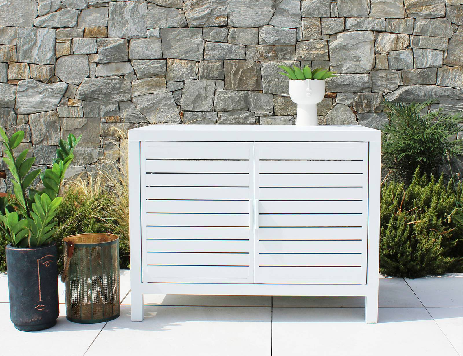 Alluminio verniciato bianco per il mobiletto Sonne di Milani Home chiuso da due ante a persiana: è funzionale, leggero e resistente. Le dimensioni contenute permettono di sistemarlo anche su un balcone stretto. Misura L 90 x P 55 x H 70 cm. Prezzo 499 euro. https://www.milanihome.it