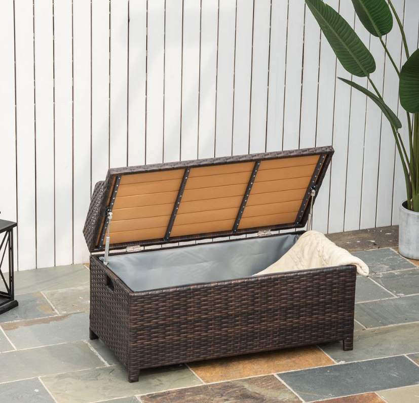 La panca contenitore multiuso di Outsunny in vendita su Aosom è rivestita in PE effetto Rattan intrecciato marrone scuro su un telaio in alluminio. Il piano di seduta per due persone è in materiale plastico a doghe. Misura L 102 x P 51 x H 52 cm. Prezzo 225,95 euro. https://www.aosom.it