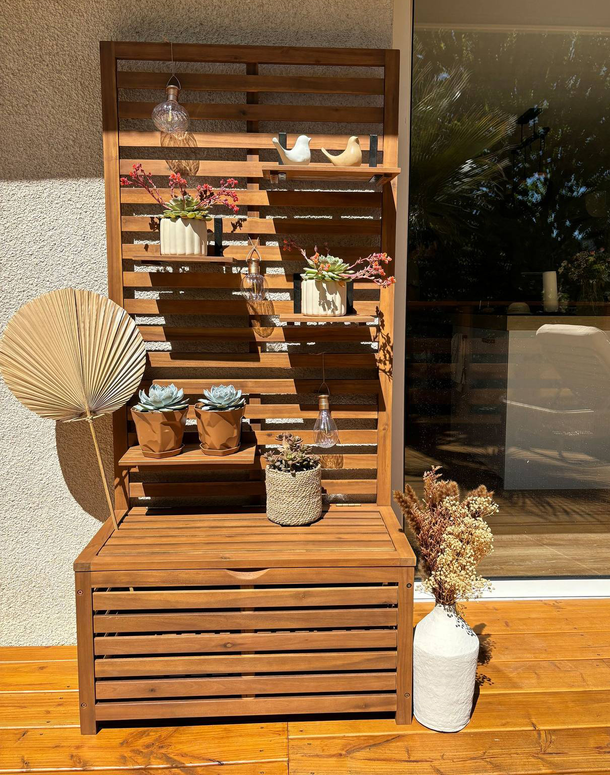 La panca da giardino Matino di Beliani è dotata di un vano contenitore e di un pannello a muro con ripiani che possono essere posizionati a piacere. La struttura a doghe è realizzata in legno massiccio di acacia, resistente alle intemperie. Misura L 80 x P 40 x H 170 cm. Prezzo 209,99 euro. https://www.beliani.it