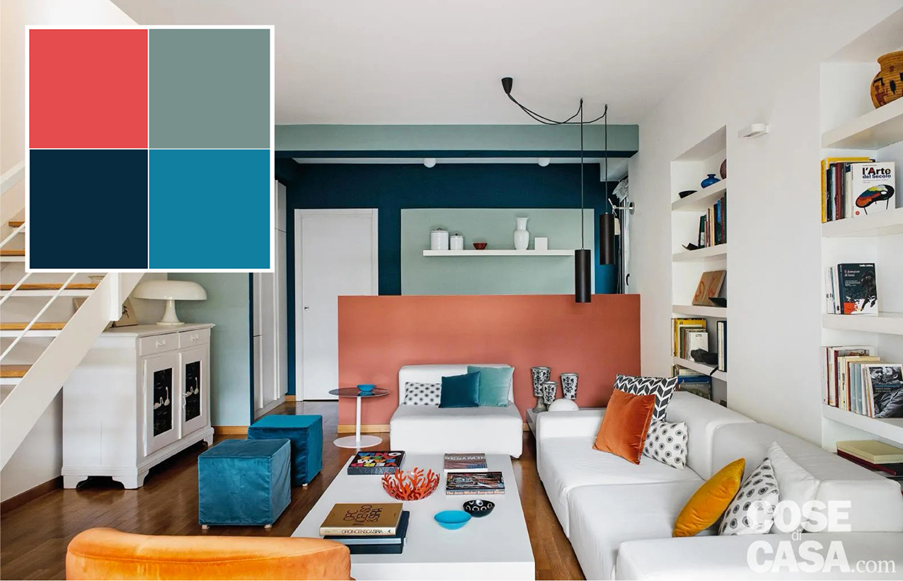 In questo open space che ospita la zona giorno, le aree pranzo e salotto sono separate dalla cucina per mezzo di un muretto alto 120 cm che funge da quinta e nasconde la zona operativa dell'angolo cottura con lavandino e fornelli. Il muretto è stato dipinto in una bella e intensa tonalità corallo che evidenzia il divisorio e mette in luce la funzionalità dell'elemento architettonico, e allo stesso tempo crea uno stacco visivo rispetto all'arredo del salotto. Infatti il corallo del muretto si sposa con il bianco delle pareti, del soffitto, dei divani in tessuto di lino, della credenza, della libreria in nicchia e del tavolino in laccato e con il color petrolio dei pouf in velluto.
Progetto e styling arch. Clara Bona, Studio98, Milano http://www.studio98.it - Foto Studio Roy