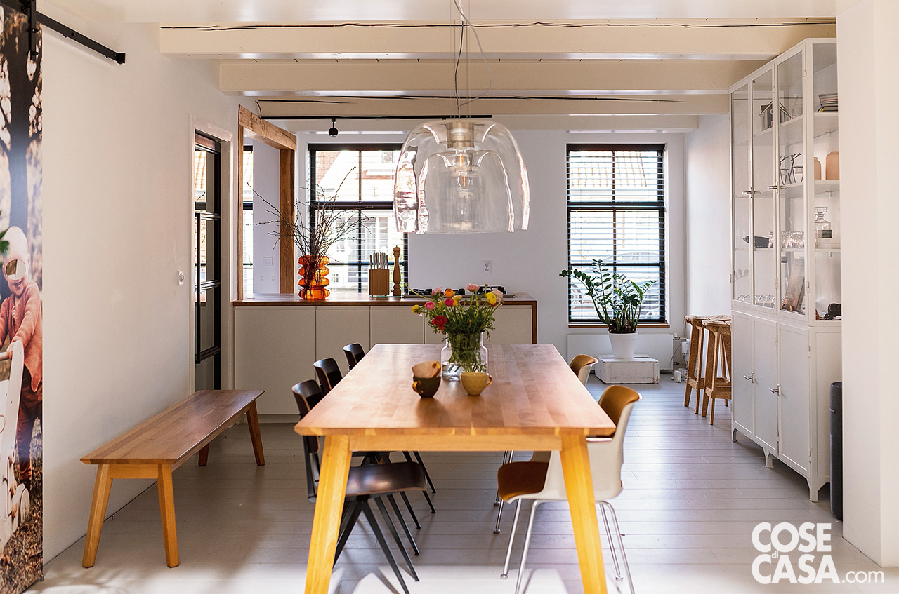 ZONA PRANZO A DOPPIO AFFACCIO La zona pranzo si colloca in posizione baricentrica, in asse con l’ingresso e tra le due aperture principali: il passaggio sul giardino e il collegamento visivo con il piano superiore tramite gli inserti in vetro. Il tavolo, realizzato artigianalmente in legno massello, è accompagnato da sedie spaiate in stile scandinavo, mentre un lampadario a sospensione in fibra intrecciata sottolinea la centralità dell’area. ZONA PRANZO A DOPPIO AFFACCIO La zona pranzo si colloca in posizione baricentrica, in asse con l’ingresso e tra le due aperture principali: il passaggio sul giardino e il collegamento visivo con il piano superiore tramite gli inserti in vetro. Il tavolo, realizzato artigianalmente in legno massello, è accompagnato da sedie spaiate in stile scandinavo, mentre un lampadario a sospensione in fibra intrecciata sottolinea la centralità dell’area.