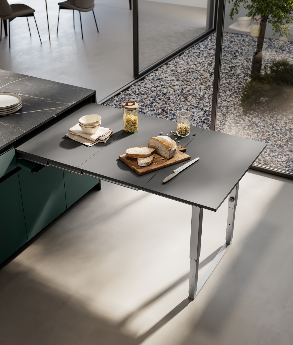 Il tavolo estraibile Party  di Arredo3 è un meccanismo estraibile posizionabile sotto a un piano di lavoro. Da chiuso, si nota solo un frontalino realizzato nella stessa finitura della cucina; per utilizzarlo si apre il frontalino e si tira verso di sé fino a estrarre completamente il piano composto da tre pannelli. Si possono allora far ruotare verso il basso le gambe di sostegno, che si trovano allineate sotto il piano, poi accompagnarle fino a terra. Fa parte del catalogo Flex, qui inserito nella composizione Kalì 9. Party, aperto, misura 85 x 137 cm. www.arredo3.it