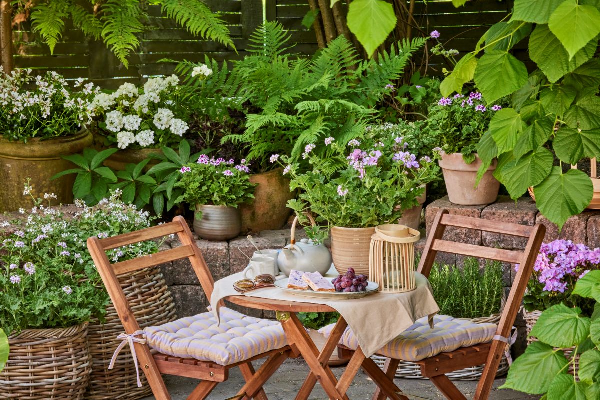 Durante la stagione calda, gli spazi esterni possono trasformarsi in un soggiorno all'aria aperta. Lo stile boho – mediterraneo si distingue per l'uso di materiali naturali e di tocchi di colore. Mobili in legno semplici e lineari si ravvivano quindi grazie alla pennellate cromatiche di fiori dai colori accesi, disposti in vasi o in cesti eleganti che rendono l'atmosfera rilassata e accogliente. Copyright immagine Pelargonium for Europe