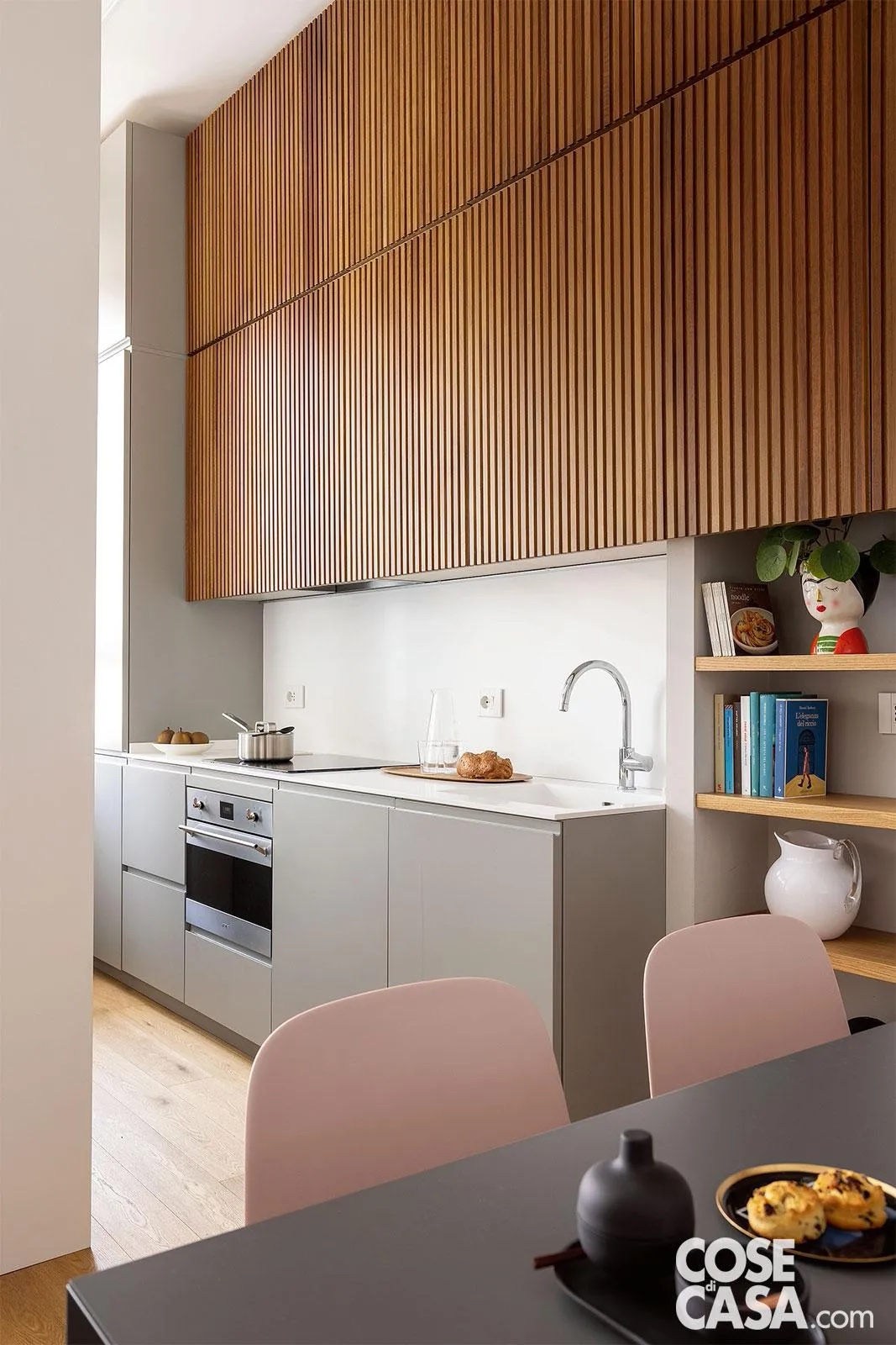 Questa cucina, laccata grigio opaco, è posta in un open space che comprende anche salotto e area pranzo. Lo spazio piccolo ha fatto optare per una composizione lineare con tutto su una sola parete. Le basi includono lavello e lavastoviglie, tra loro vicini, fornello e forno, uno sopra l'altro, e uno spazio dispensa. La colonna frigo, posizionata all'estremità verso la finestra, per creare meno ingombro, è l'unico elemento alto. Nella parte superiore, i pensili sono mascherati da ante effetto boiserie a listelli di legno, particolarmente decorativa. Progetto Studiocarta, arch. Mauro Carta, Silvia Faravelli, Andrea Villa, Milano, Tel. 02/38239040 http://www.maurocarta.com - Foto Cristina Galliena Bohman - Styling Rosaria Sofia Galli Questa cucina, laccata grigio opaco, è posta in un open space che comprende anche salotto e area pranzo. Lo spazio piccolo ha fatto optare per una composizione lineare con tutto su una sola parete. Le basi includono lavello e lavastoviglie, tra loro vicini, fornello e forno, uno sopra l'altro, e uno spazio dispensa. La colonna frigo, posizionata all'estremità verso la finestra, per creare meno ingombro, è l'unico elemento alto. Nella parte superiore, i pensili sono mascherati da ante effetto boiserie a listelli di legno, particolarmente decorativa. Progetto Studiocarta, arch. Mauro Carta, Silvia Faravelli, Andrea Villa, Milano, Tel. 02/38239040 http://www.maurocarta.com - Foto Cristina Galliena Bohman - Styling Rosaria Sofia Galli