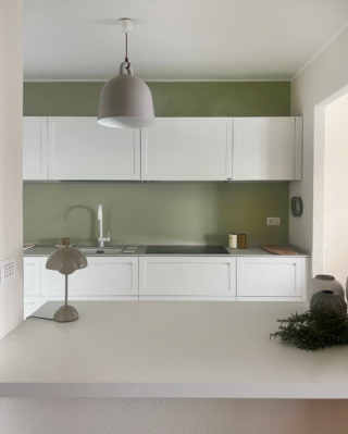 In questa cucina di una casa al lago la parete di fondo è stata dipinta con un verde salvia intenso che crea un contrasto netto con i mobili, che invece sono stati scelti nel colore più neutrale possibile: il bianco. Ecco un’idea semplicissima ma di grande resa. Più il colore è strong e scuro, più lo stacco sarà totale. In questo caso il verde salvia e il bianco creano un contrasto lieve e riposante, seppure di impatto. I pensili, volutamente interrotti prima del soffitto, accentuano la cesura cromatica e sottolineano la relazione tra i due piani di colore.