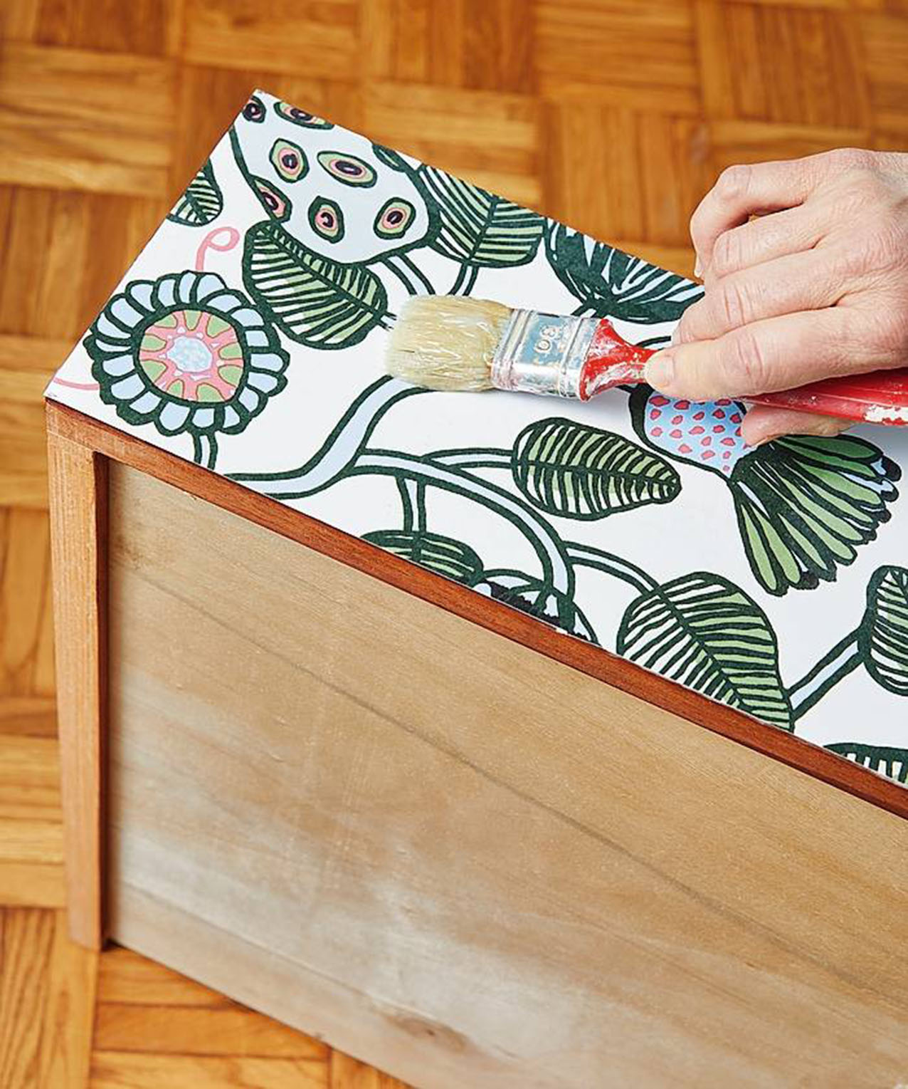 Tagliare la carta da parati destinata alla parte frontale dei cassetti, applicandola con la colla. Prestare attenzione a mantenere la sequenza dei decori per ricomporre il disegno originale. Tagliare la carta da parati destinata alla parte frontale dei cassetti, applicandola con la colla. Prestare attenzione a mantenere la sequenza dei decori per ricomporre il disegno originale.