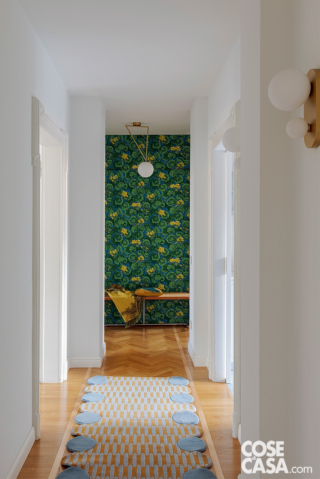 Corridoio total white con sfondo tappezzato in verde, blu e giallo