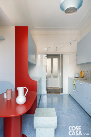 Cucina azzurra con tavolo e fianco sagomato rossi e nuove porte scorrevoli in vetro trasparente