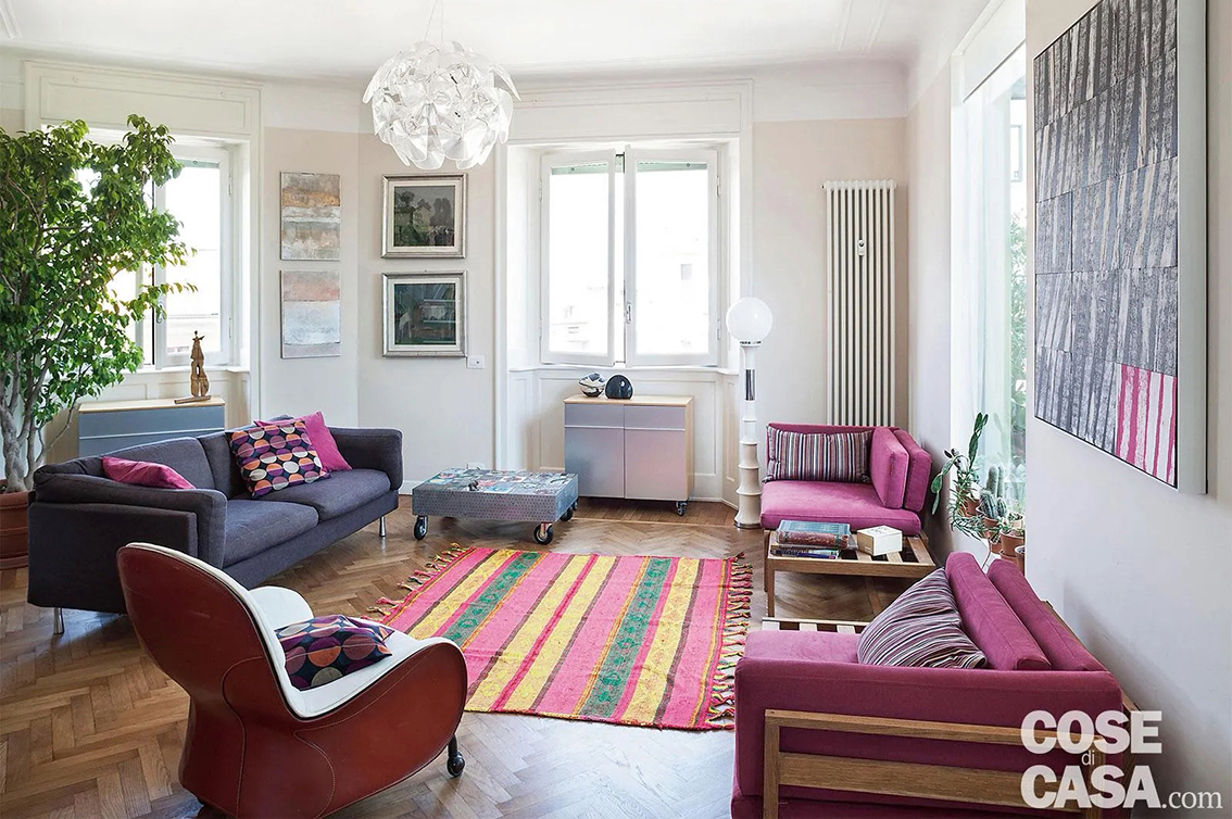 In questo salotto il fucsia è uno dei colori che ravvivano l'ambiente: il tappeto-stuoia centrale alterna infatti delle bande di diversi colori, tra cui appunto il fucsia, il verde e il giallo.
Nella stanza, molto luminosa e dotata di pareti bianche, sono mescolati in modo sapiente ed equilibrato dei tocchi di tonalità diverse, come il grigio del divano e il viola delle poltrone e di alcuni cuscini: l'insieme, lungi dall'essere eccessivo nonostante il mix di colori, risulta molto gradevole.
Progetto Studio A2architetti, Milano, a2architetti.it@gmail.com - Foto Cristina Fiorentini