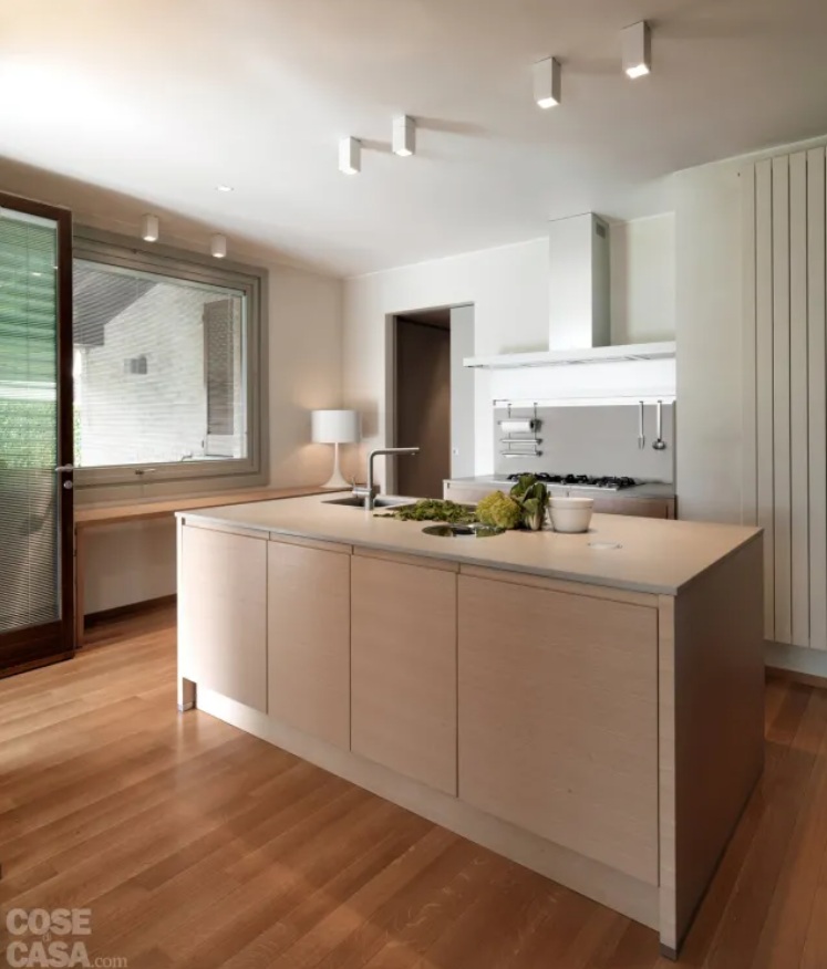 L’isola al centro della cucina - attrezzata nella parte inferiore con basi in rovere naturale - permette di disporre di un’ampia superficie di lavoro sul top: quest’ultimo è in pietra ricomposta (di Stone Italiana), un materiale che si ottiene addizionando a frammenti di pietra naturale una percentuale di resina. Per le pareti è stata scelta una finitura in tonalità chiara grigio-avorio, ottenuta con un particolare prodotto “in pasta antica”: l’effetto estetico sfumato sulla superficie dei muri richiama quello degli stucchi d’epoca tradizionali. Come nel resto della casa la finitura artigianale a calce delle pareti è della ditta De Carlini.