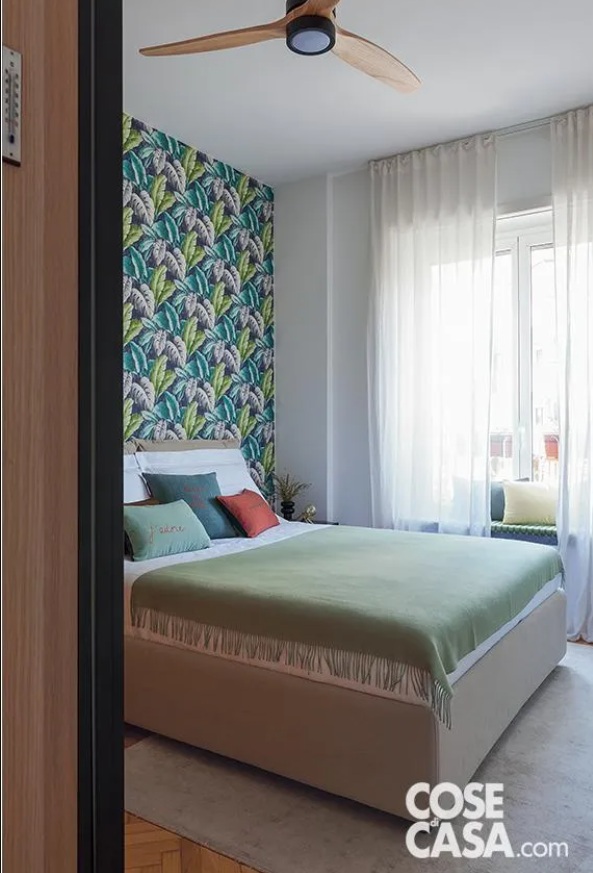 Nella camera matrimoniale il letto tessile color écru con testiera imbottita e contenitore sotto la rete è di Ikea, con biancheria e coperta di Marina C. e cuscini di Pois a righe. La parete di fondo è rivestita con carta da parati a motivo jungle, modello Verena di Tapeten der 70er. Il comodino a destra è di LaForma-Barcelona living. Il ventilatore a soffitto è di Ikohs. Nella camera matrimoniale il letto tessile color écru con testiera imbottita e contenitore sotto la rete è di Ikea, con biancheria e coperta di Marina C. e cuscini di Pois a righe. La parete di fondo è rivestita con carta da parati a motivo jungle, modello Verena di Tapeten der 70er. Il comodino a destra è di LaForma-Barcelona living. Il ventilatore a soffitto è di Ikohs.