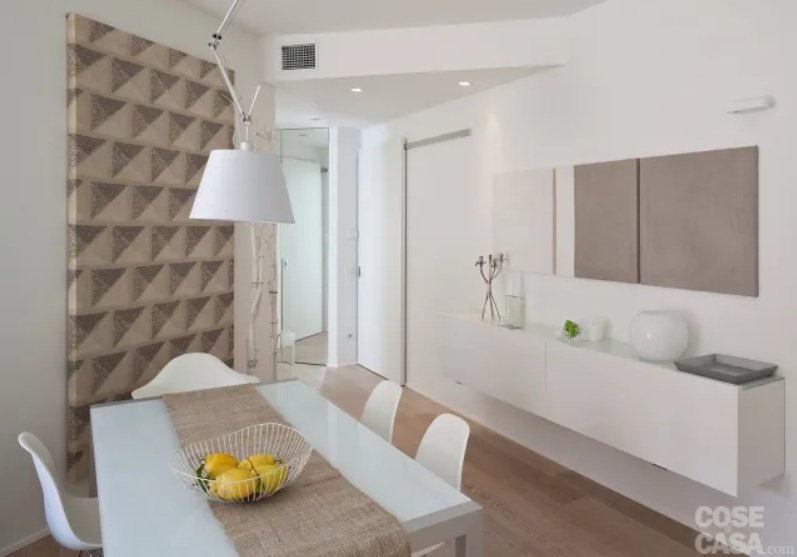 Nella zona pranzo alle spalle del tavolo – sopra il mobile sospeso – la parete è decorata con tre pannelli in tessuto che riprendono le tonalità dominanti della casa: bianco ed écru. Nella zona pranzo alle spalle del tavolo – sopra il mobile sospeso – la parete è decorata con tre pannelli in tessuto che riprendono le tonalità dominanti della casa: bianco ed écru.