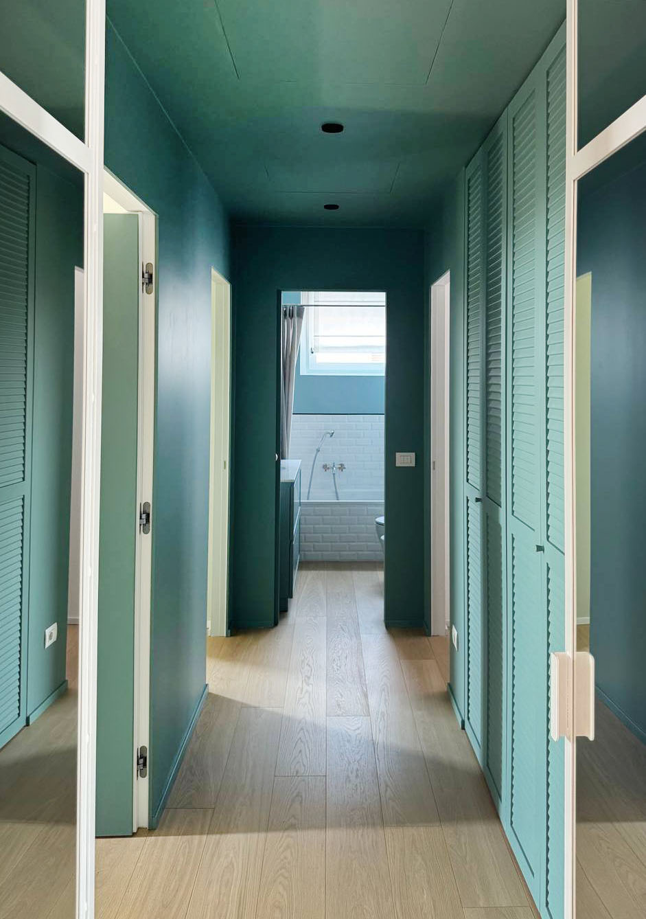 In questo corridoio si voleva uno zoccolino che non si vedesse troppo. È stato quindi posato uno zoccolino di altezza minima, 2 centimetri, che è stato poi dipinto a smalto color ottanio: come abbinare in casa questo particolare verde-blu, esattamente della stessa tinta delle pareti e delle porte. In questo modo l’effetto finale tende a sparire.